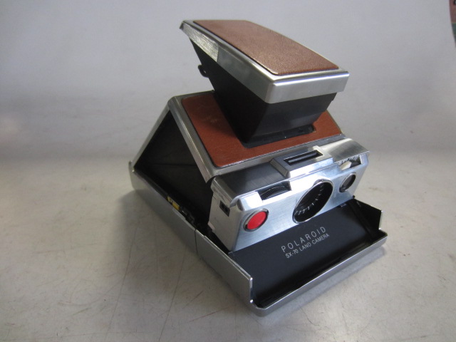 Polaroid SX-70 Land Camera, With Neck Strap. Uses Polaroid SX 70 film, readily available as of 04/23/2019.  Introduced: 1972, Tan, Polaroid, 1970s+, Metal, 1"H, 4"W, 7"L
