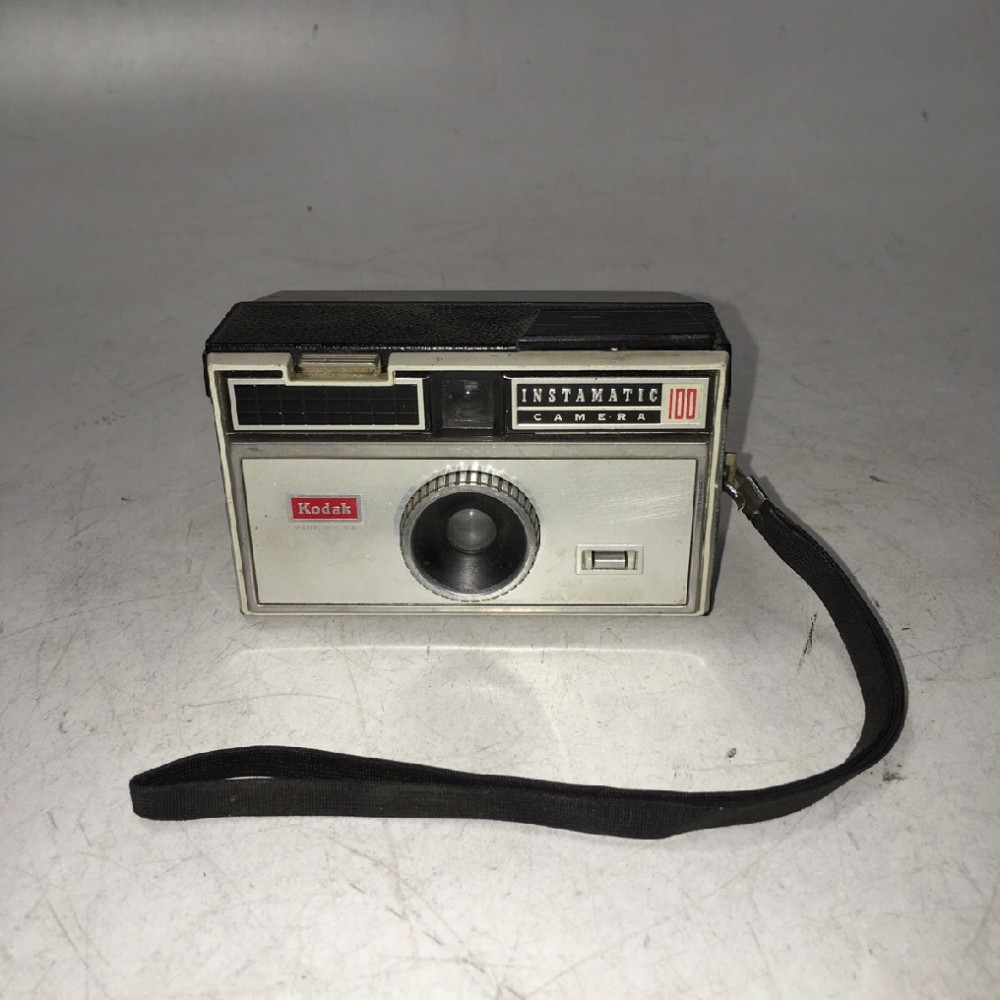 Kodak Instamatic 100 with wrist strap.  Manufactured 1963-1966. Uses two AAA bateries to power AG1 flashbulb (sold seperately). , Black, Kodak, 1960+, Metal